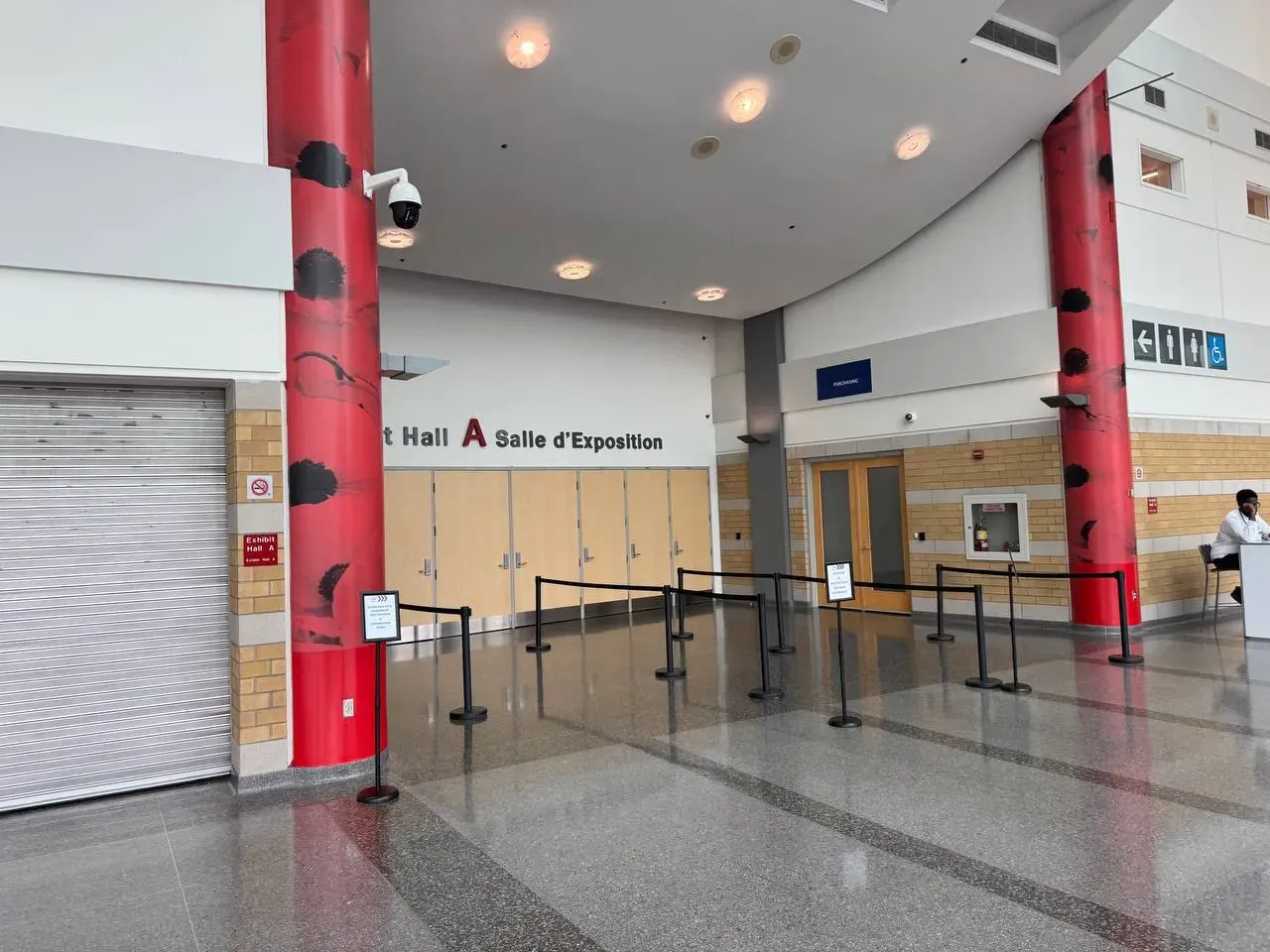Black belt stanchions and two sign stands forming a queue in an exhibition hall foyer